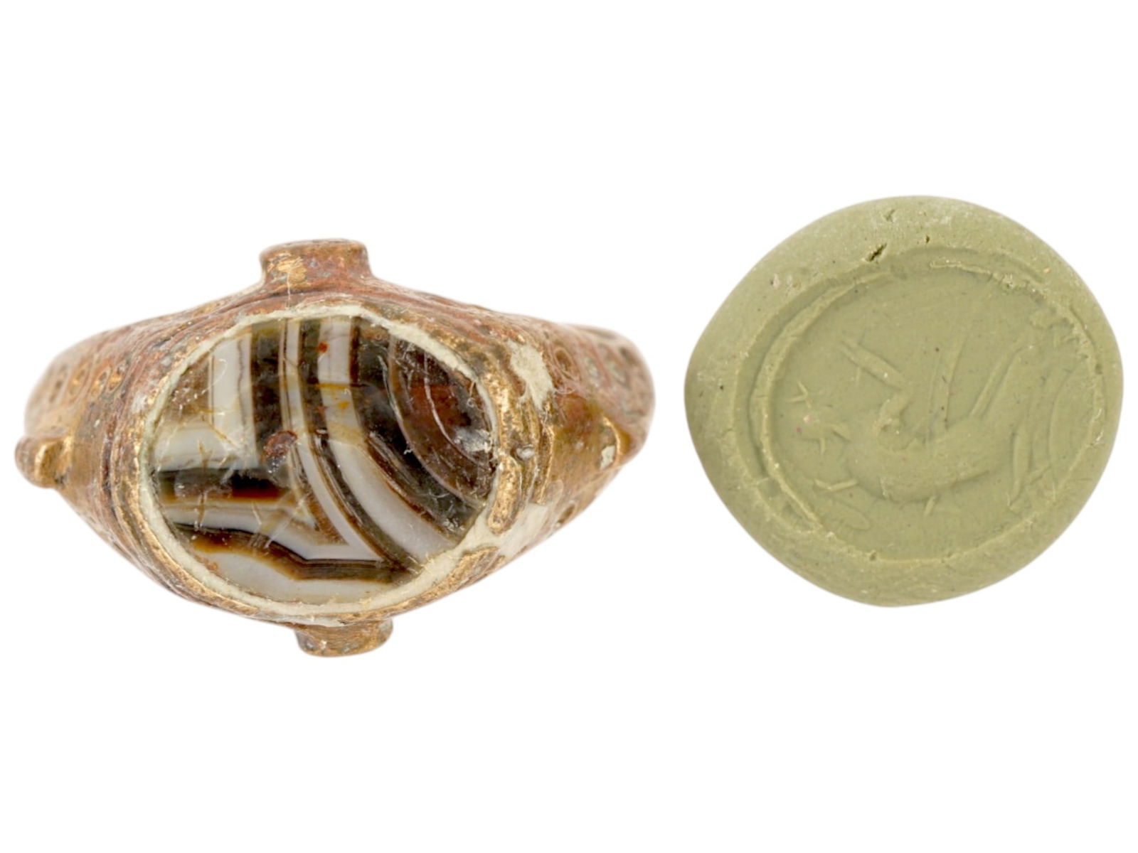 ANCIENT CARVED AGATE BRONZE SIGNET RING INTAGLIO: An ancient bronze signet ring intaglio with a massive shield. The central part is made of banded agate stone. A figure is carved into the stone, which, when imprinted, creates a relief image depicting