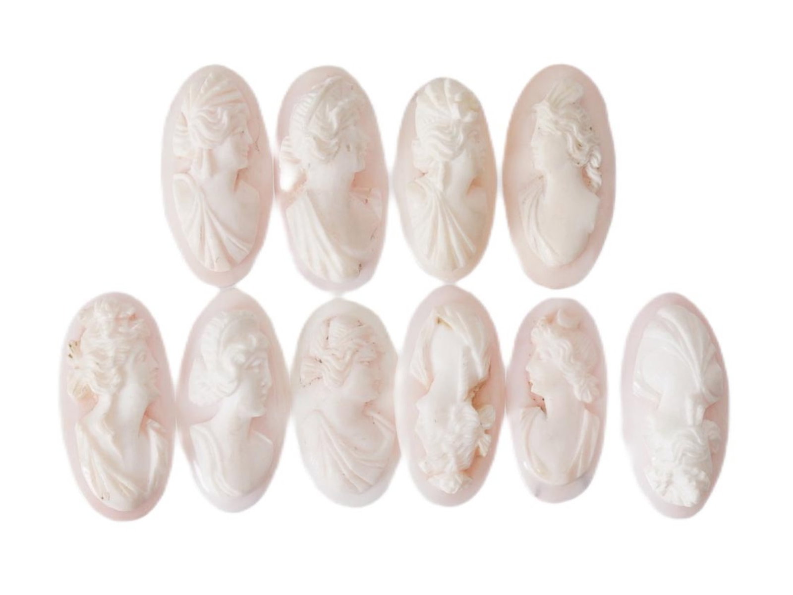 COLLECTION OF FEMALE PORTRAIT CARVED CORAL CAMEOS: A collection of hand carved pink Coral cameos. A total of 10 items. Each piece depicts a female profile portrait rendered in high relief. Oval shape. Collectible Jewelry And Glyptic Art, Sculpture.