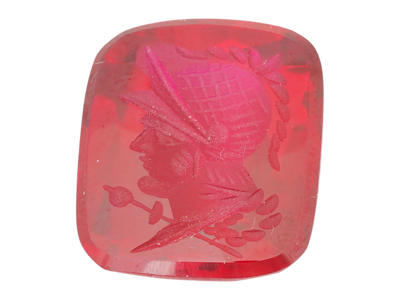 RED GLASS CAMEO ENGRAVED WITH WARRIOR PORTRAIT: A red glass cameo with an engraved warrior profile portrait to the left. The cameo is rectangular and smooth at the front, while the back is intricately faceted. Engraved in the center is a portrait o