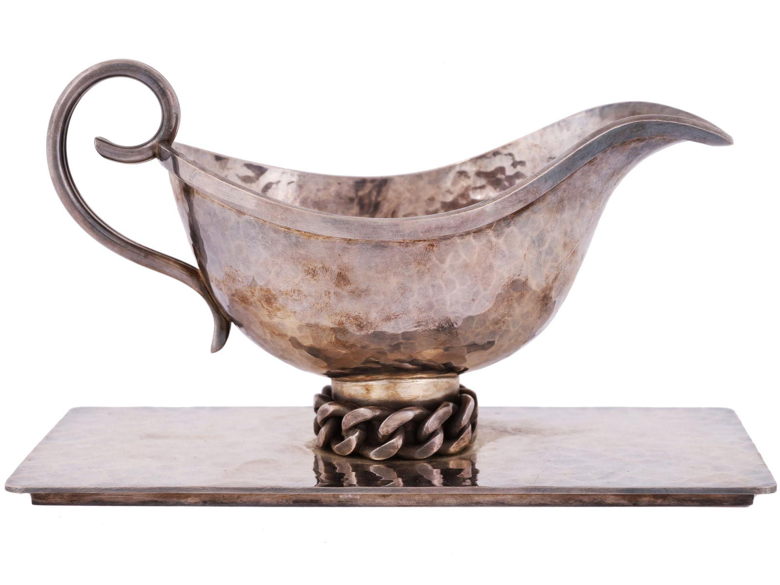 ANTIQUE SILVER PLATED GRAVY BOWL BY JEAN DESPRES: An antique silver plate gravy boat by Jean Despres, French, 1889 to 1980. The ware is made in a hammered texture design. Mounted on foot made in a chain link design. Signed with engraving and dated, 1