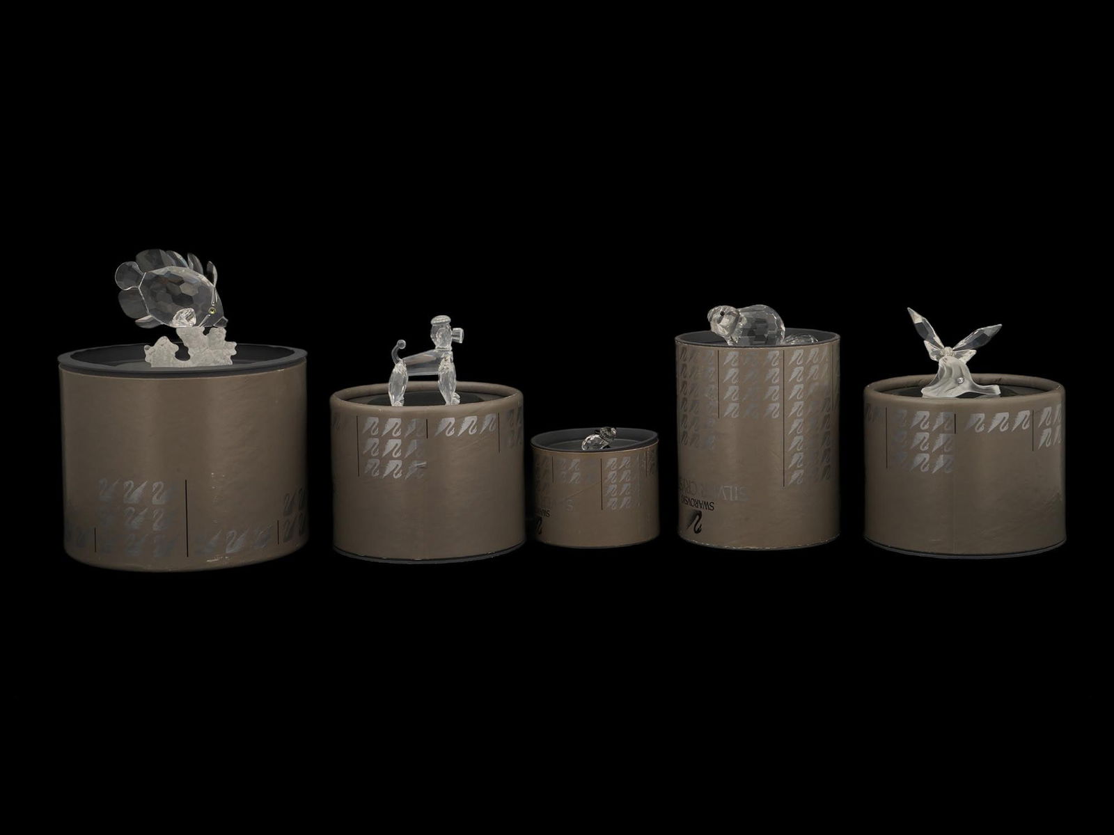 GROUP OF THREE SWAROVSKI CRYSTAL FIGURINES IOB: A group of three Swarovski crystal figurines in their original cylindrical boxes. The lot includes: a Fish, a Poodle, a Small Panda figurine, a Beaver and a Butterfly. Comes with Swarovski certificate