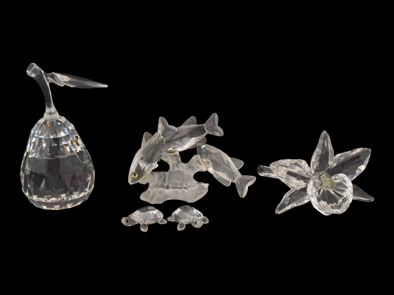 GROUP OF SWAROVSKI FACETED CRYSTAL FIGURINES: A group of Swarovski faceted crystal figurines. It includes a Pear figurine, Three South Sea Fish figurine with small colored eyes, swimming around a frosted coral base, Orchid flower and a pair of sm