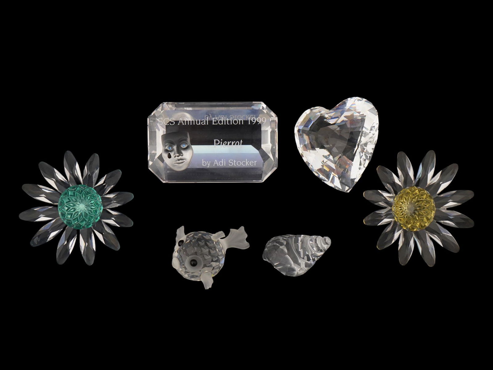 GROUP OF SIX SWAROVSKI FACETED CRYSTAL FIGURINES: A group of six Swarovski faceted crystal figurines. It includes a Crystal Society Annual Edition 1999 plaque featuring an etched sad clown face design by designer Adi Stocker. A clear, multifaceted cr