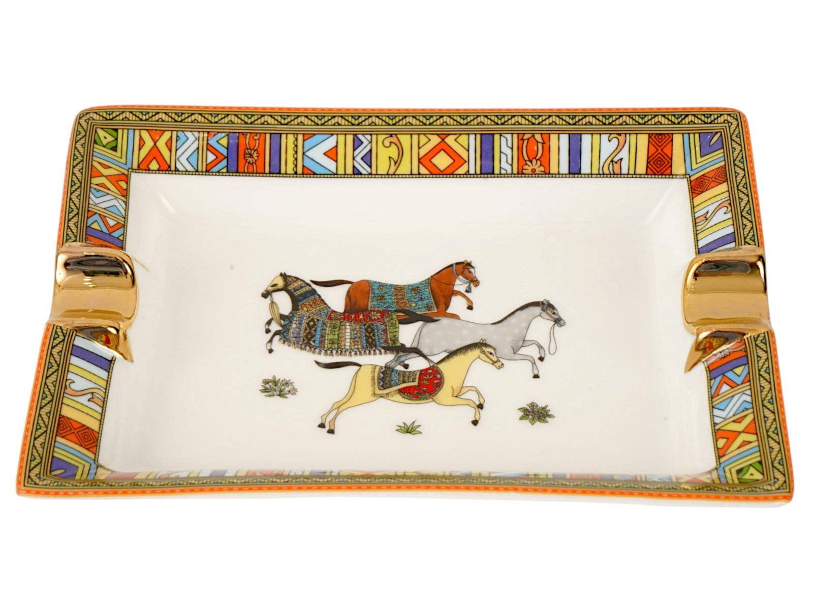 VINTAGE FRENCH HERMES CERAMIC CIGAR ASHTRAY WITH HORSES: A vintage French Hermes ceramic cigar ashtray featuring an ornate equestrian-themed design. The center depicts four horses adorned with decorative saddles and blankets, framed by a vibrant geometric b
