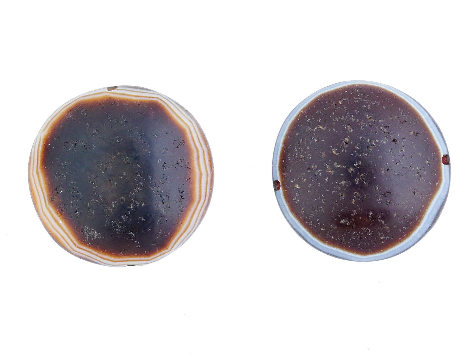 ANCIENT CARVED POLISHED NATURAL AGATE STONE BEADS: A pair of ancient carved and polished natural agate stone beads. Round beads of brown color with a light pattern along the edge and through holes. Probably of ancient Roman origin. Historical Collecti