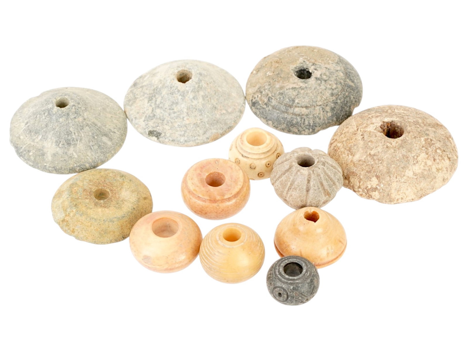 COLLECTION OF 12 ANCIENT HOLY LAND SPINDLE WHORLS: A collection of 12 ancient Holy Land spindle whorls features various sizes and shapes with different designs. Circa 300 BC to 300 AD. Their detailed engravings highlight both artistic precision and fu