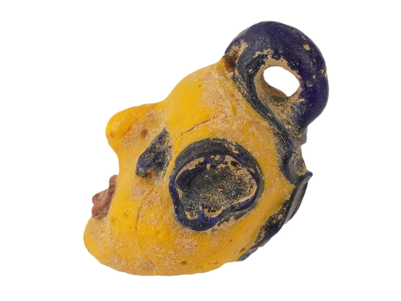 GRECO ROMAN MULTICOLORED MOSAIC GLASS AMULET PENDANT: A Greco Roman multicolored mosaic glass amulet pendant, artfully crafted in the shape of a head in yellow, blue and red. Circa 300 BC to 100 BC. This artifact showcases the remarkable artistry and cul