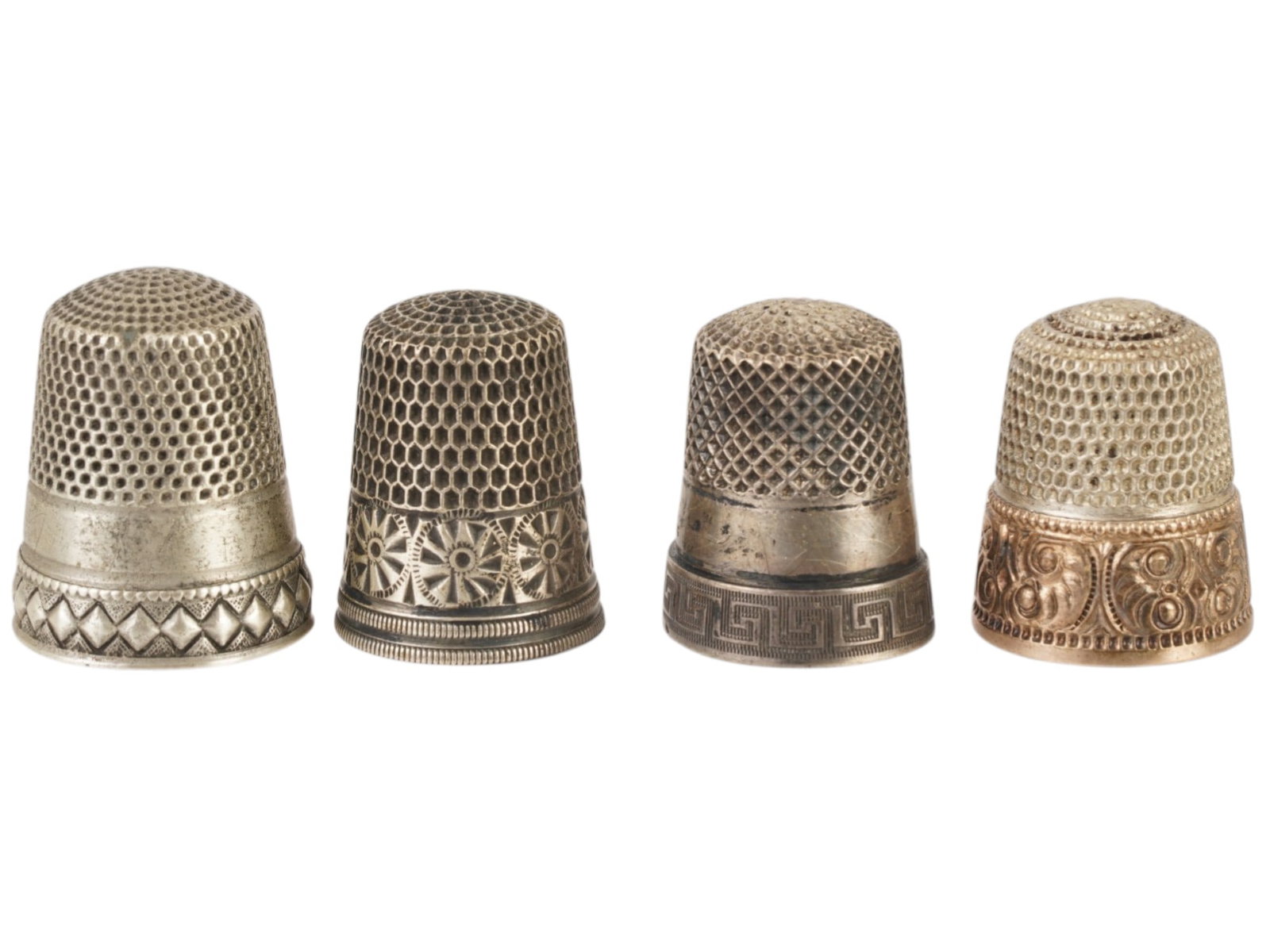 GROUP OF FOUR ANTIQUE THIMBLES SOME MARKED SILVER: A group of four antique thimbles, dating from the 19th to early 20th century. Typically made in silver, the thimbles feature practical honeycomb or dimpled tops for grip, along with decorative bands