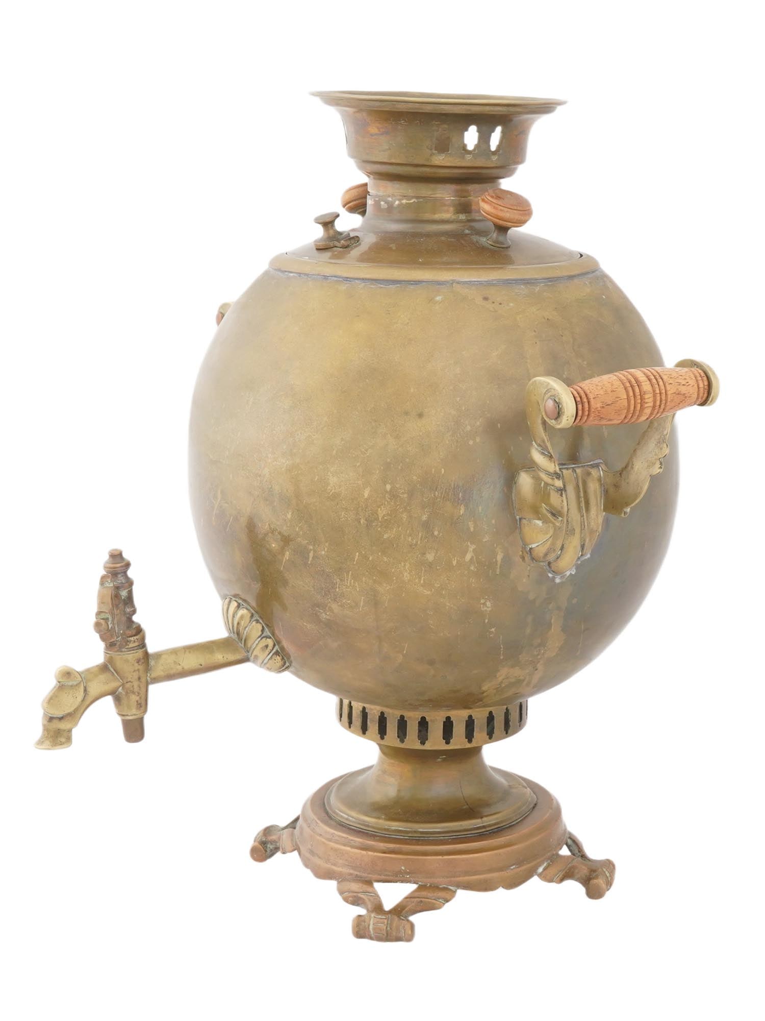 ANTIQUE LITHUANIAN BRASS SAMOVAR: An antique brass samovar from Lithuania. A container for boiling water. The samovar has a classic spherical body with a domed lid topped by a small knob and ventilation holes. It features two ornate w