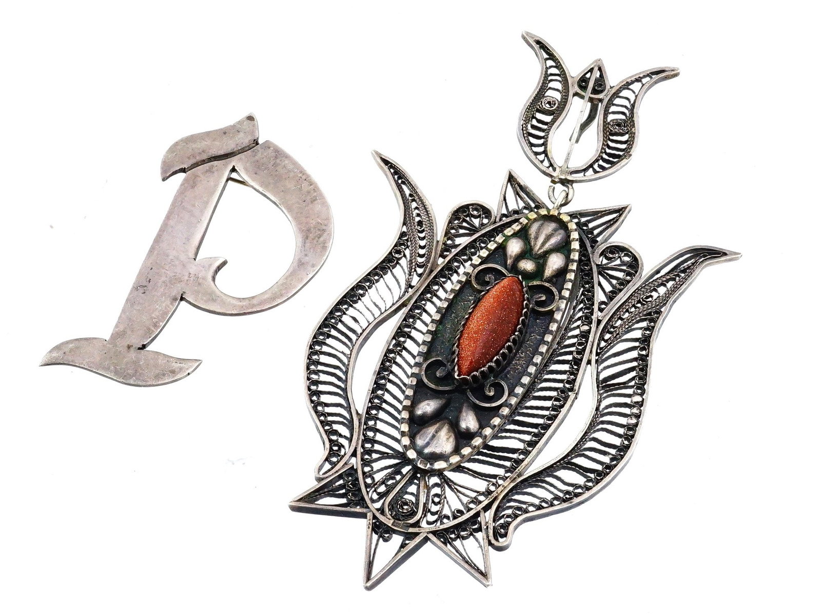 VINTAGE SILVER FILIGREE BROOCH AND MONOGRAM PIN: Two vintage silver pins dating from approximately the 1950s to 1970s. The larger piece is an ornate silver filigree brooch, set with a cabochon and surrounded by twisted-wire scrollwork forming a styl