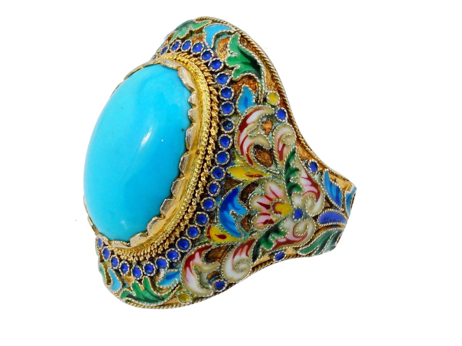 RUSSIAN GILT SILVER CLOISONNE ENAMEL TURQUOISE RING: A Russian gilt silver and enamel statement ring. The ring is set with a large oval turquoise cabochon to the center. A band is adorned with polychrome enamel floral, foliage, foliate scroll and geomet