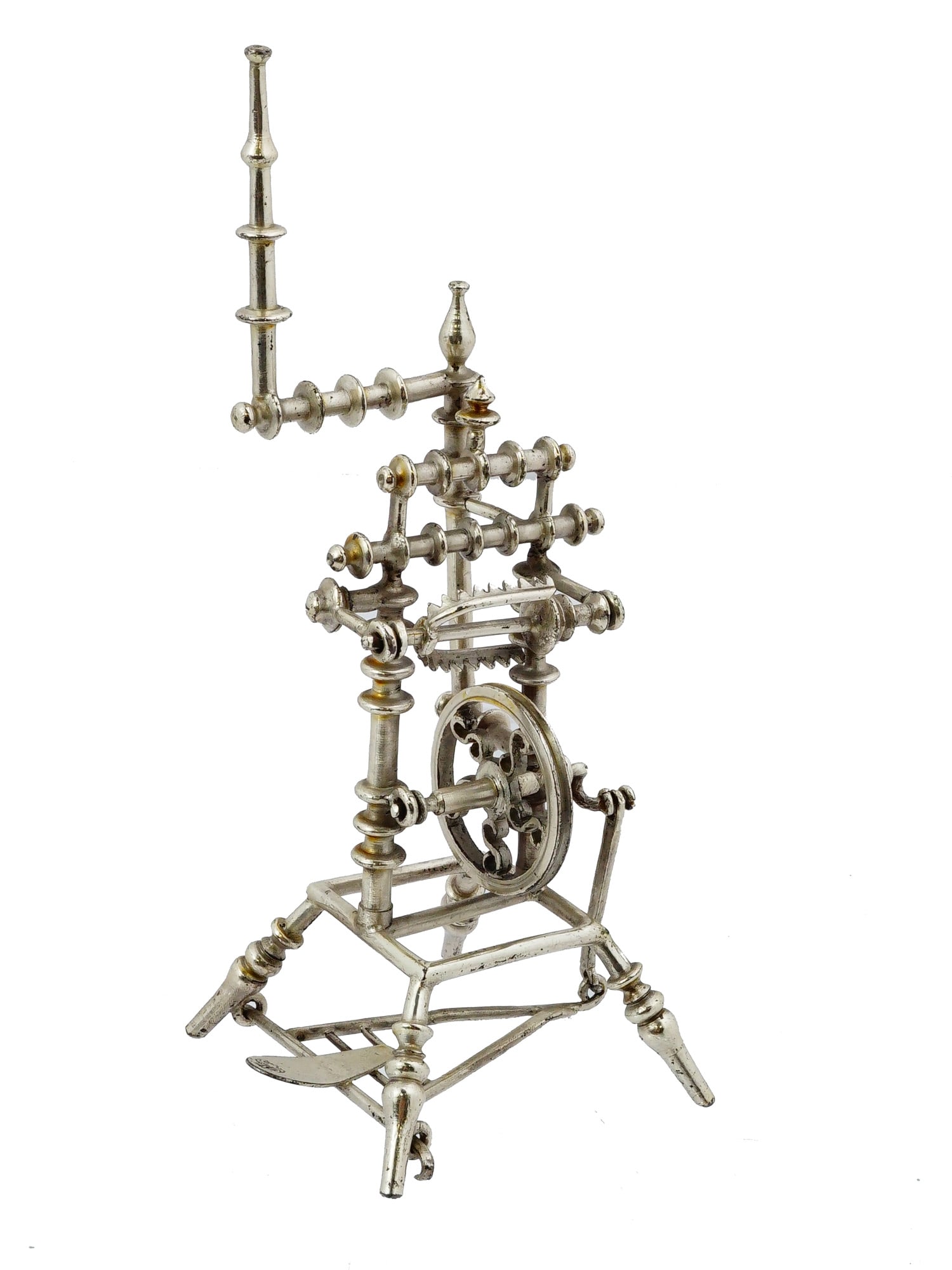 MINIATURE VINTAGE SILVER SPINNING WHEEL: A miniature vintage silver spinning wheel, crafted as a decorative collectors piece. Features detailed elements such as turned pillars, a central drive wheel, and a distaff, with many examples