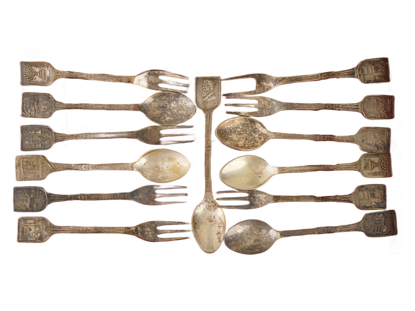 LOT OF VINTAGE ISRAELI SOUVENIR FORKS AND SPOONS: A lot of vintage Israeli souvenir cutlery. A total of 6 spoons, 6 three-pronged forks, and a two-pronged fork. The handle tips feature relief symbols, architectural sights, portraits, and inscriptions