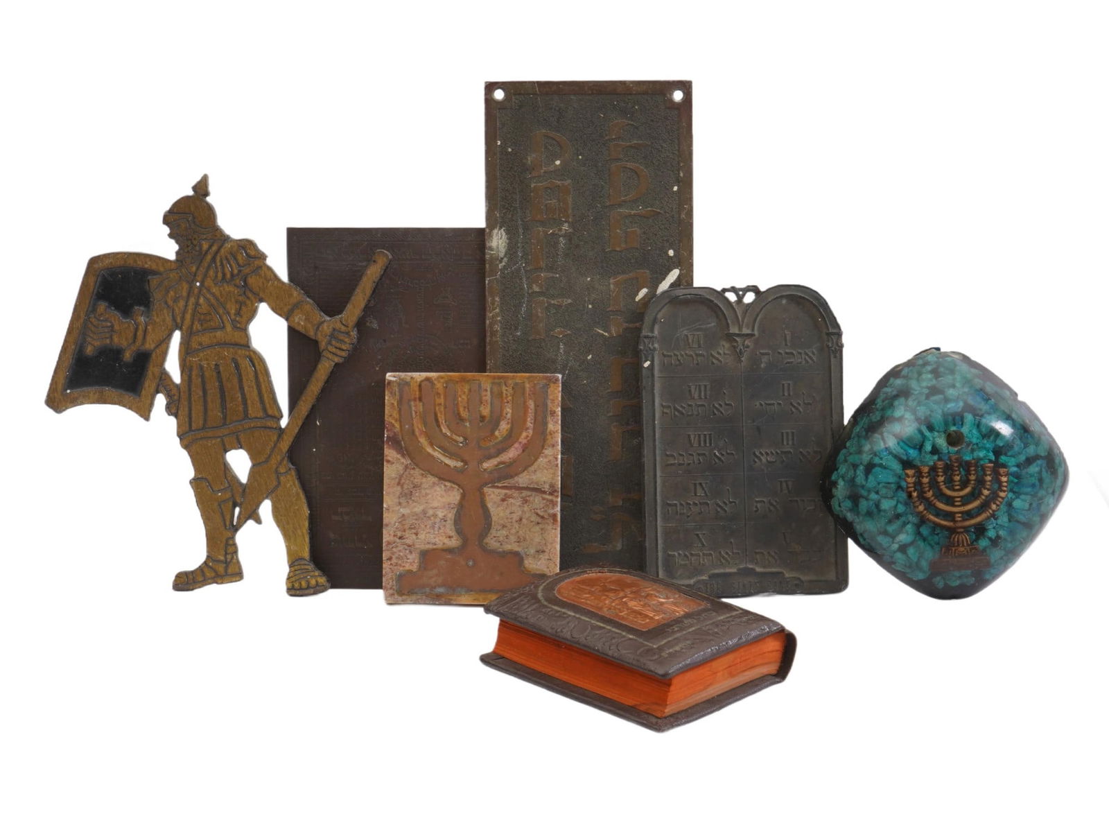 ASSORTMENT OF JEWISH ISRAELI DECORATIVE METAL ITEMS: An assortment of Jewish Israeli decorative metal items, featuring several Judaica motifs. The collection includes a metal cut-out figure of a soldier holding a shield and spear, a small Bezalel book,
