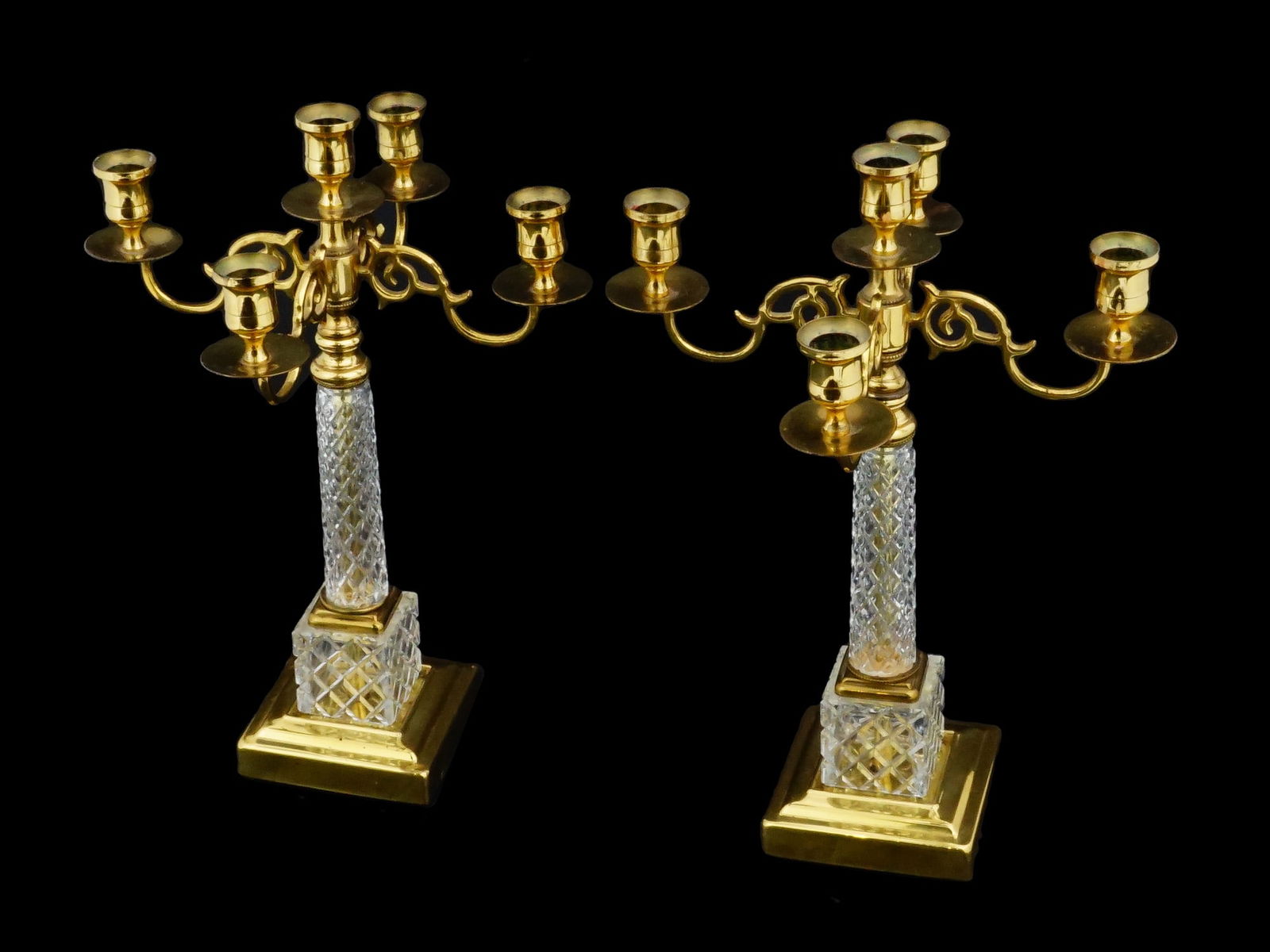 PAIR OF NEOCLASSICAL STYLE FIVE LIGHT CANDELABRAS: A pair of Neoclassical style five-light candelabras, each featuring a central fluted crystal column rising from a tiered square crystal base. The gilt bronze mounts include four scrolling foliate