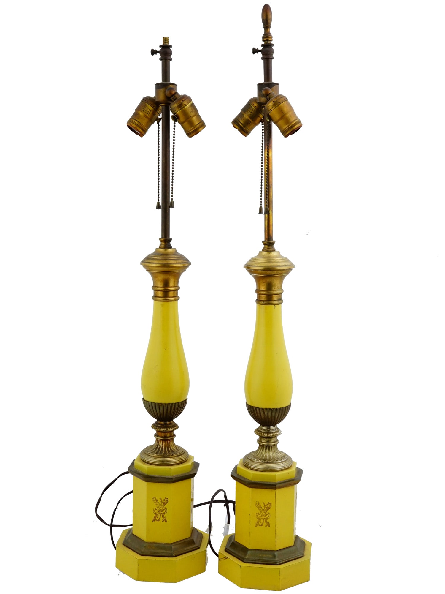 TWO YELLOWISH TOLE LAMPS WITH BRASS FITTINGS: A lot of two yellowish tole lamps with brass fittings. The lamps feature tall columnar bases with twin sockets. Painted yellow. ?ome with electrical wires. Presumably of American origin. Home Decor An