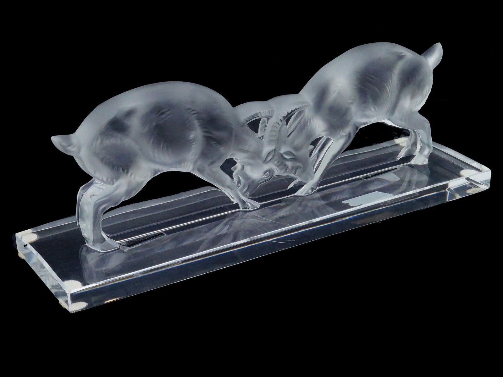 FRENCH LALIQUE CRYSTAL SCULPTURE OF TWO GOATS: A French Lalique crystal sculpture, titled Deux Beliers, depicts two sparring goats rendered in a combination of frosted and polished clear crystal. The figures are captured in a dynamic, head-to-head