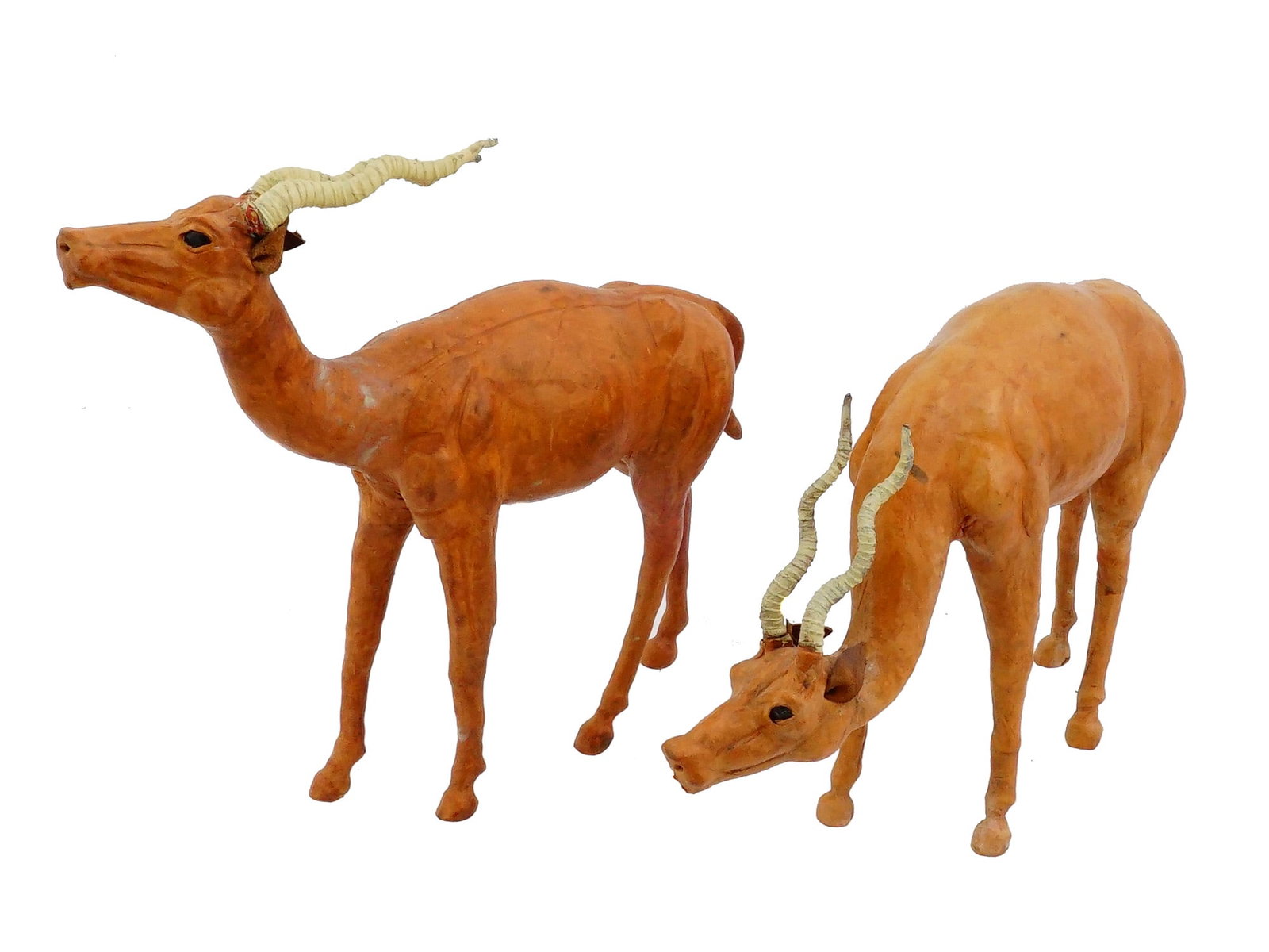 VINTAGE LEATHER WRAPPED AFRICAN GAZELLE FIGURINES: Two vintage leather-wrapped animal figurines, modeled after African antelopes or gazelles, reflect a popular mid-20th-century decorative style. The figures are covered in molded genuine leather that h