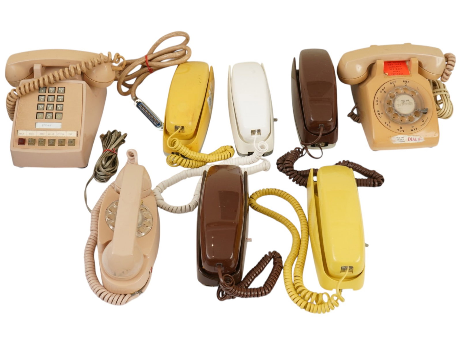 GROUP OF EIGHT VINTAGE LANDLINE TELEPHONES: A group of eight vintage landline telephones featuring a variety of mid-to-late 20th-century designs including rotary desk models, wall-mounted touch-tone units, and several Trimline-style handsets. T