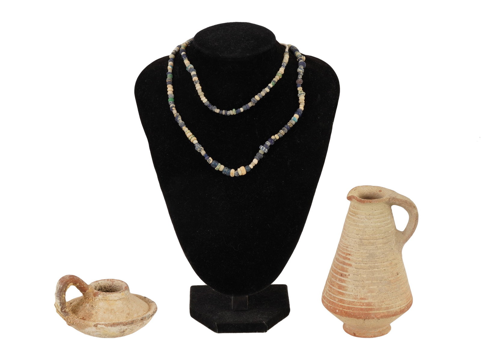 ANCIENT ROMAN JUG WITH BEAD NECKLACE BYZANTINE OIL LAMP: An ancient Roman terracotta jug, a strand of ancient glass beads, and a late Byzantine terracotta oil lamp dating to circa 200 to 800 AD. The jug reflects the simple, utilitarian pottery forms of the