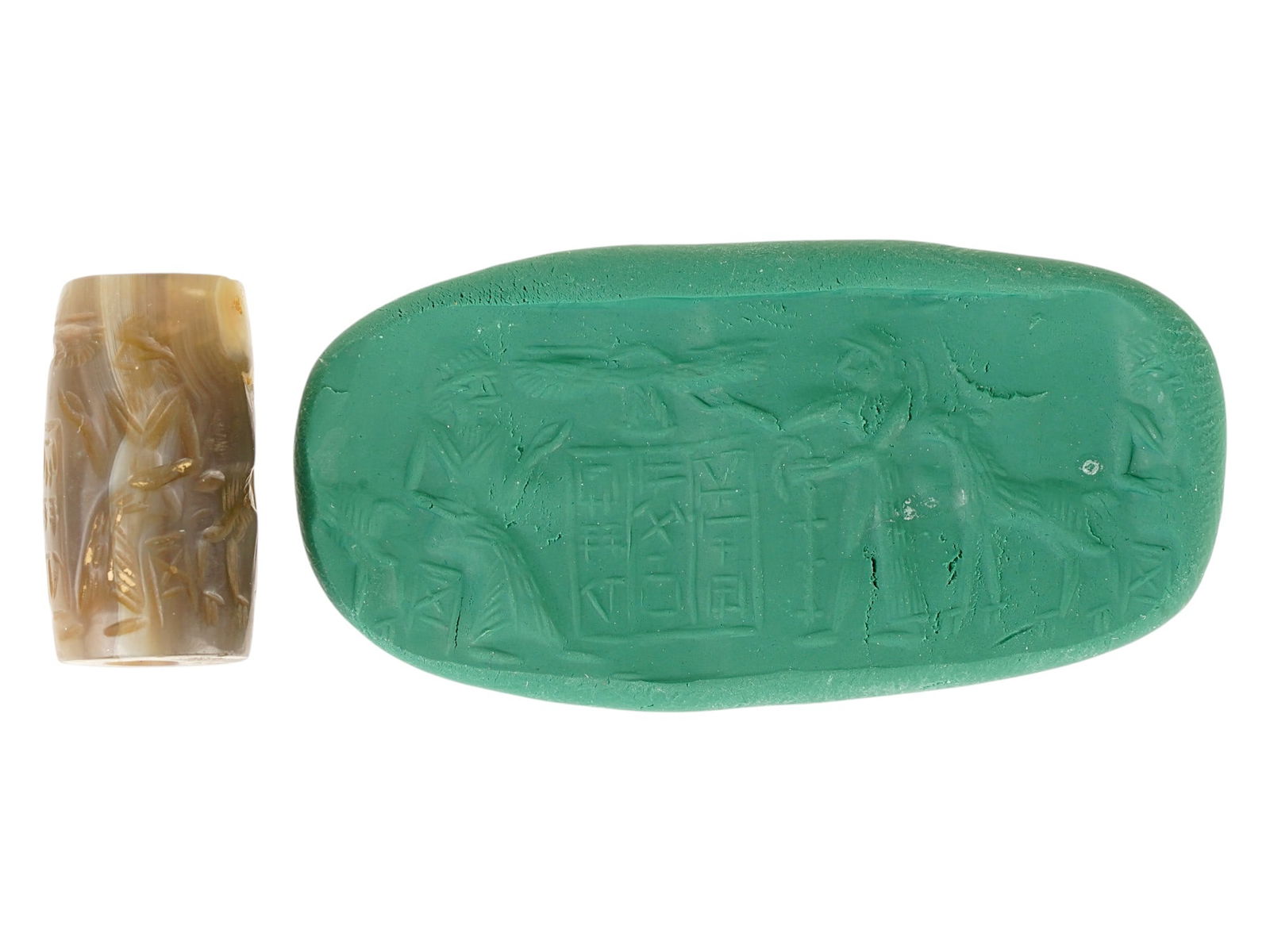 ANCIENT NEAR EASTERN CARVED AGATE BEAD CYLINDER SEAL: An ancient Near Eastern hand carved Agate stone cylinder seal bead. The impression depicts a scene of a royal ceremony or ritual featuring the composition with columns with cuneiform inscriptions, fla