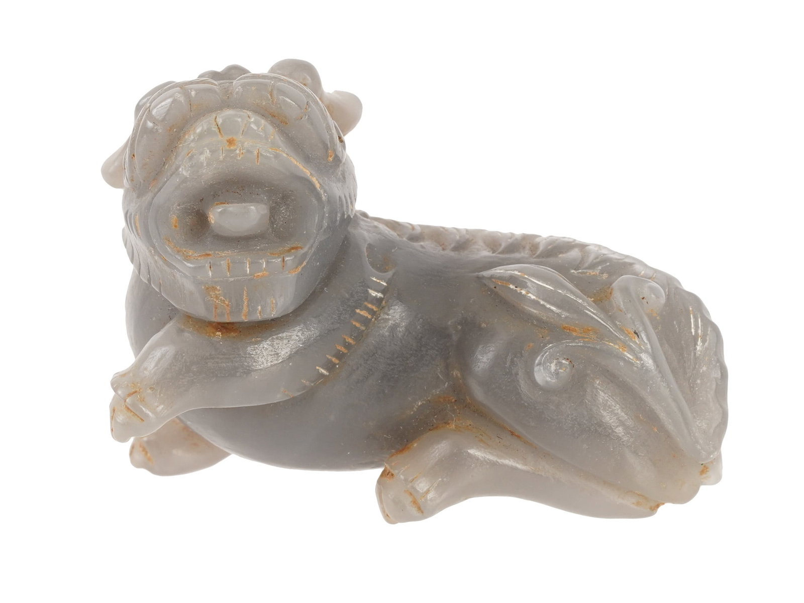 CHINESE HAND CARVED JADE PIXIU FIGURINE: A Chinese hand carved jade figurine depicts a recumbent mythical beast, possibly a bixie or pixiu. The creature is modeled with its head turned sharply to the left, featuring an open mouth, prominent