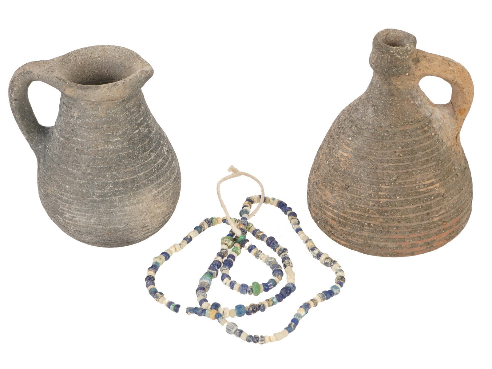 ANCIENT ROMAN TERRACOTTA PITCHERS GLASS BEAD NECKLACE: A group of two ancient Roman terracotta pitchers, dating to approximately 100 to 300 AD, accompanied by a strand of ancient glass beads. The pitchers reflect everyday Roman vessels used for storing an