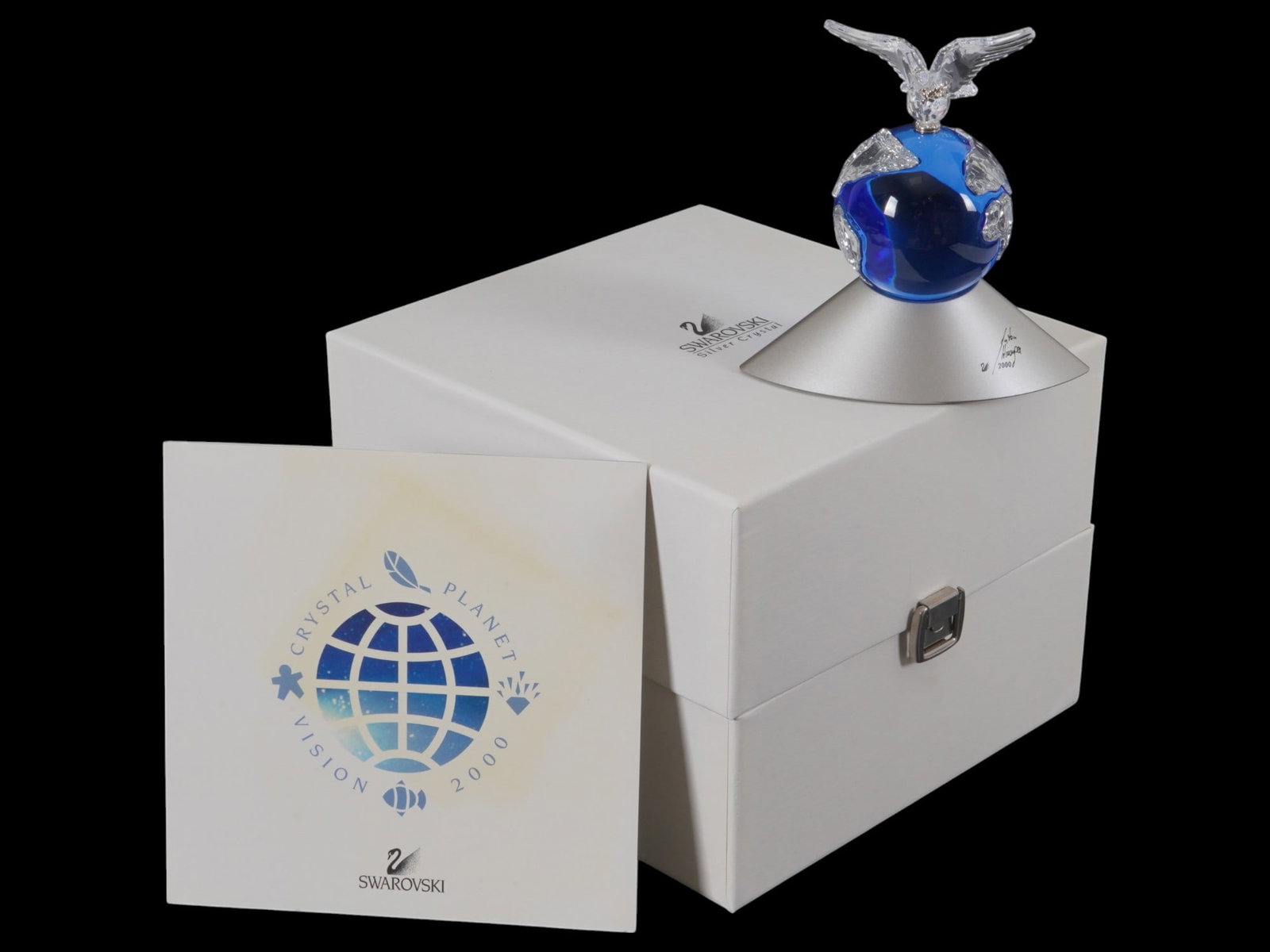 SWAROVSKI CRYSTAL PLANET FIGURE WITH DOVE IOB: A Swarovski Crystal Planet, released as a special Millennium Edition to celebrate the year 2000. A sapphire blue crystal sphere featuring land masses made of clear crystal. A clear faceted Peace Dove