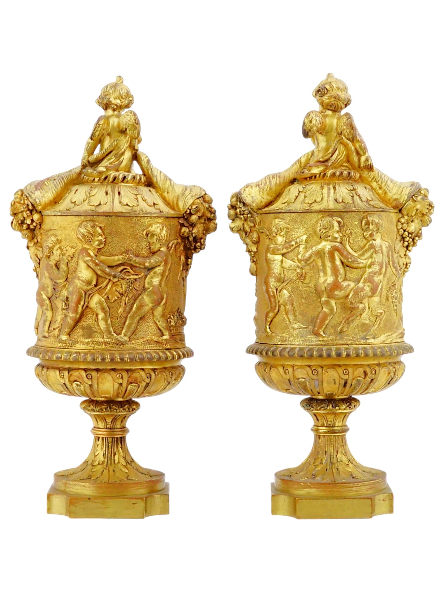 PAIR OF ANTIQUE FRENCH LOUIS XVI GILT BRONZE URNS: A pair of antique French Louis XVI style gilt bronze urns. The lidded urns are executed in a Neoclassical style, featuring cylindrical bodies decorated with high-relief mythological friezes of a multi