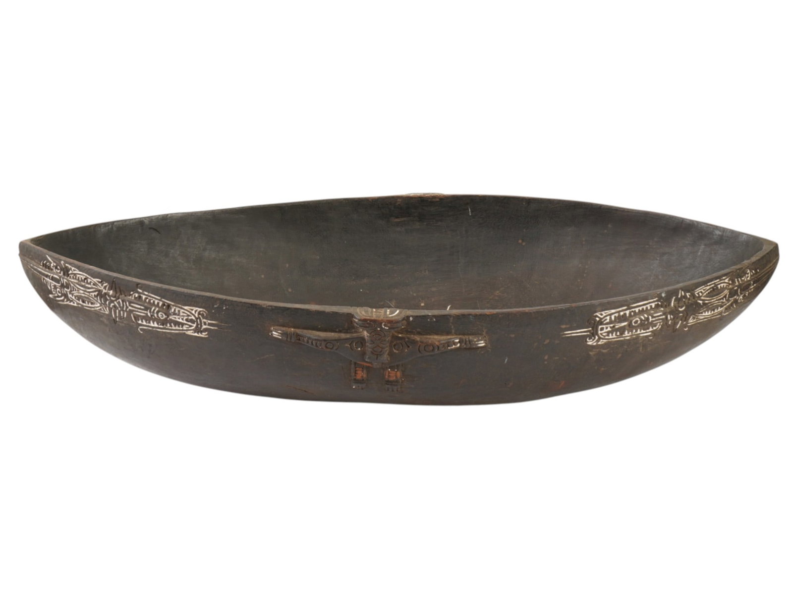 PAPUA NEW GUINEA TROBRIAND ISLANDS WOOD KAVA BOWL: A Papua New Guinea Trobriand Islands hand carved solid wood kava bowl. The exterior of the elongated bowl is decorated with low-relief carvings of crocodiles and stylized anthropomorphic effigies, acc