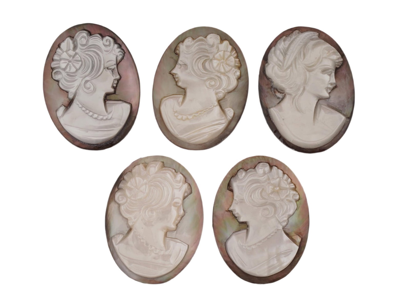 GROUP OF FIVE HAND CARVED SHELL CAMEOS W PORTRAITS: A group of five shell cameos, each featuring a hand-carved female profile in relief utilizing the naturally contrasting layers of shell. Display a light cream or white foreground set against a darker,