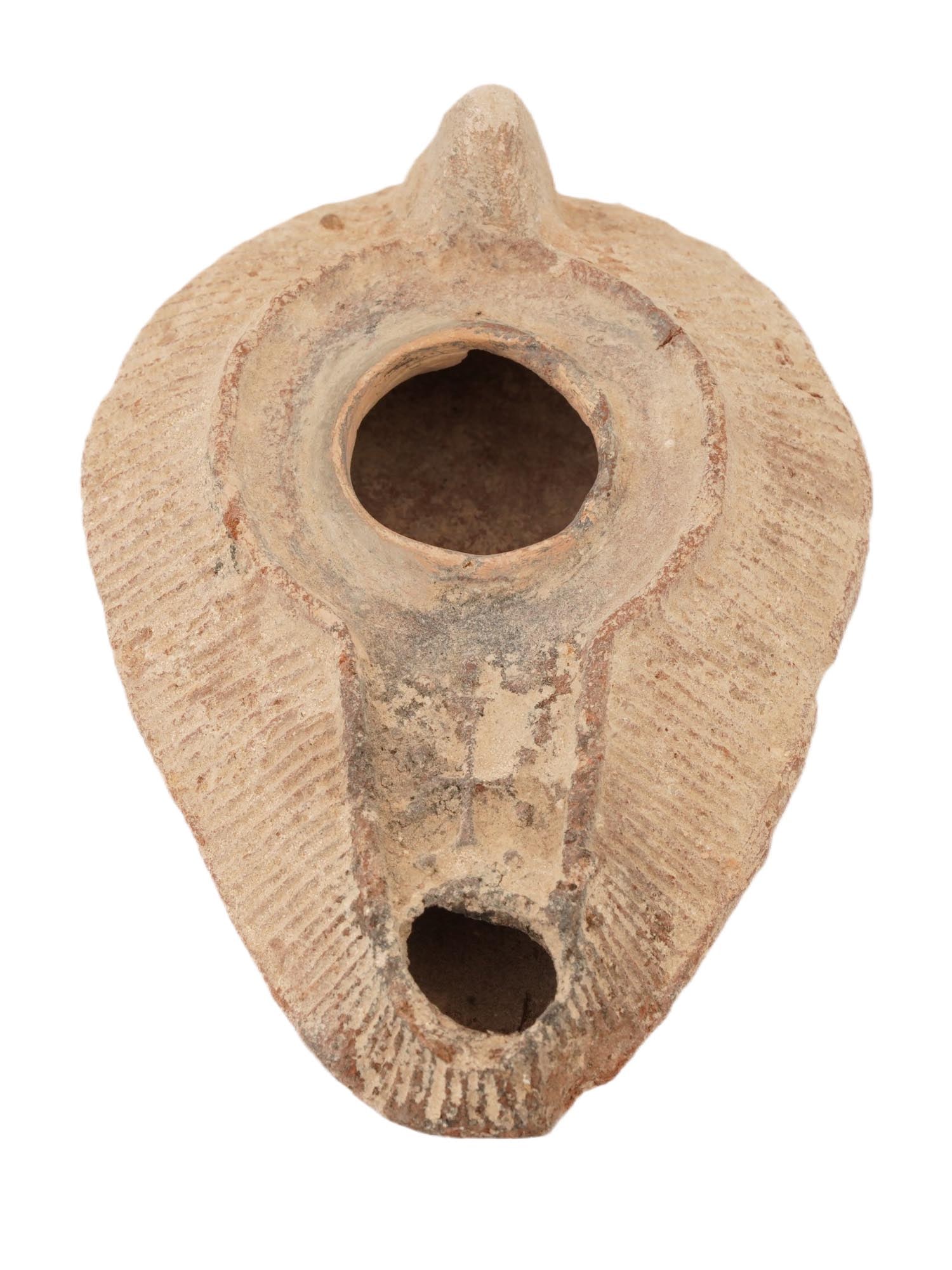 ANCIENT ROMAN BYZANTINE EMPIRE TERRACOTTA LAMP: An ancient Roman Byzantine Empire moulded terracotta lamp. The body of the ware is adorned with an engraved cross design on a spout. The body tapers in at the nozzle. Lamps such as this one are occasi
