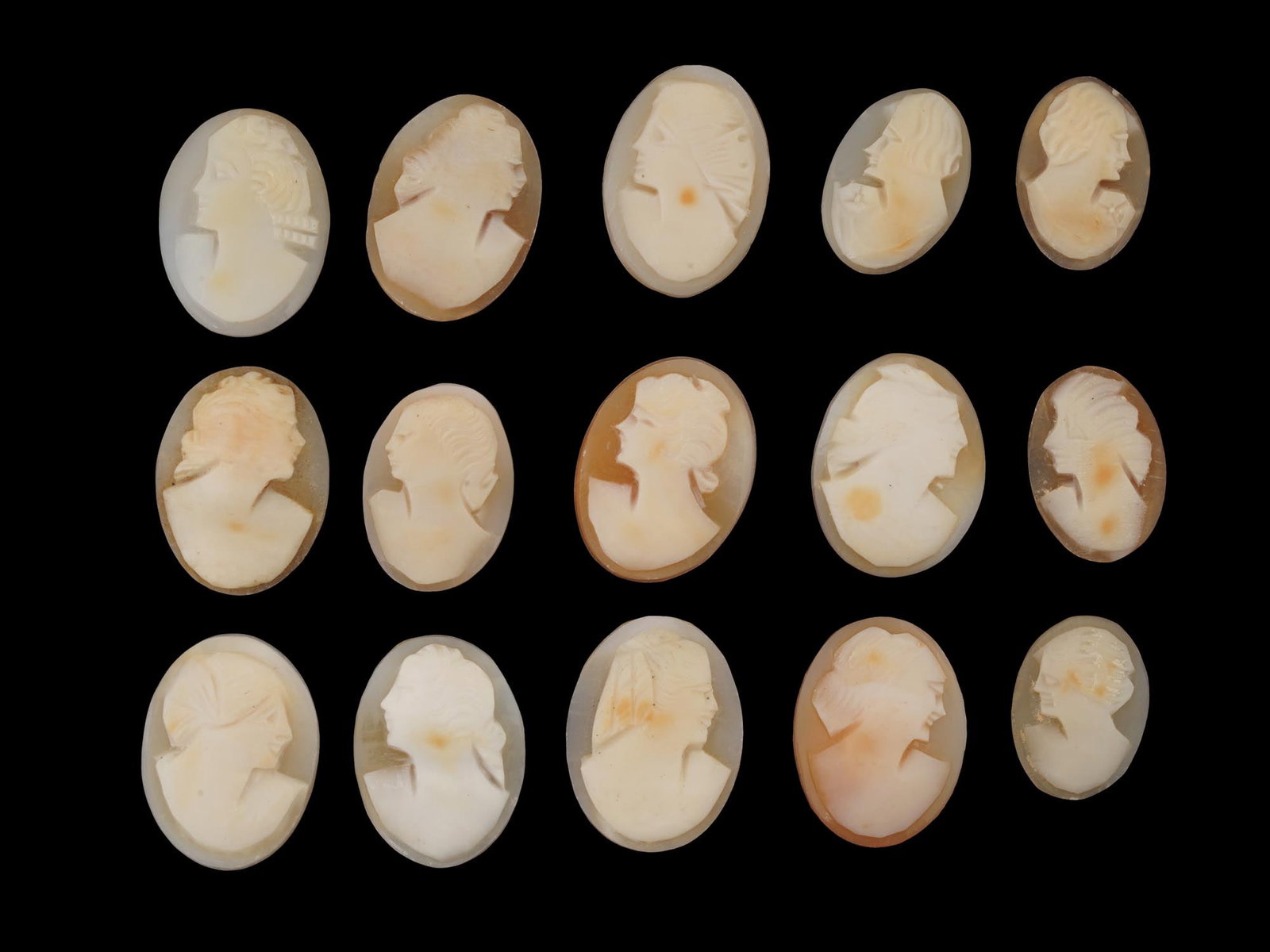 COLLECTION OF FEMALE PORTRAIT CARVED SHELL CAMEOS: A collection of hand carved shell cameos. A total of 15 items. Each piece depicts a female profile portrait rendered in high relief in the Victorian manner. Each cameo is fashioned in a distinctive ov
