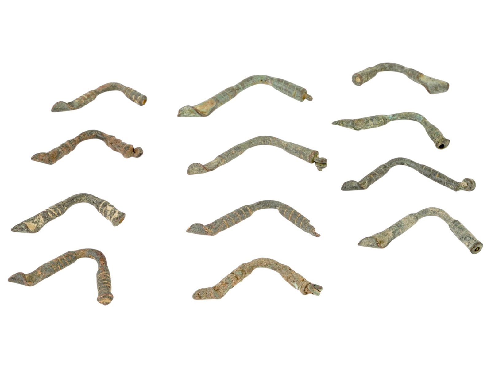 ANCIENT ROMAN BRONZE FIBULAS CIRCA 100 TO 300 AD: A group of ancient Roman bronze fibulas, dating from circa 100 to 300 AD, showcasing a variety of forms and fastening mechanisms used throughout the Roman Empire. These brooches served both practical