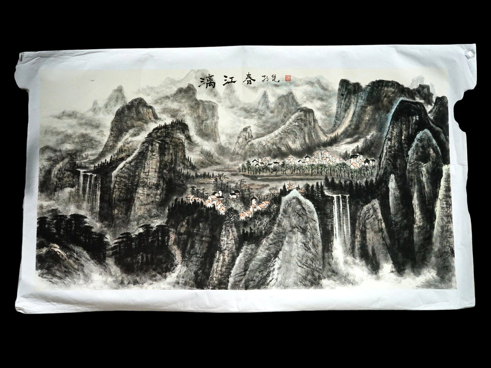 CHINESE MOUNTAIN LANDSCAPE PAINTING SIGNED: A Chinese landscape painting on paper executed in ink and light color washes. The central focus features a cluster of white-walled dwellings with terracotta-colored roofs situated amidst a grove of st