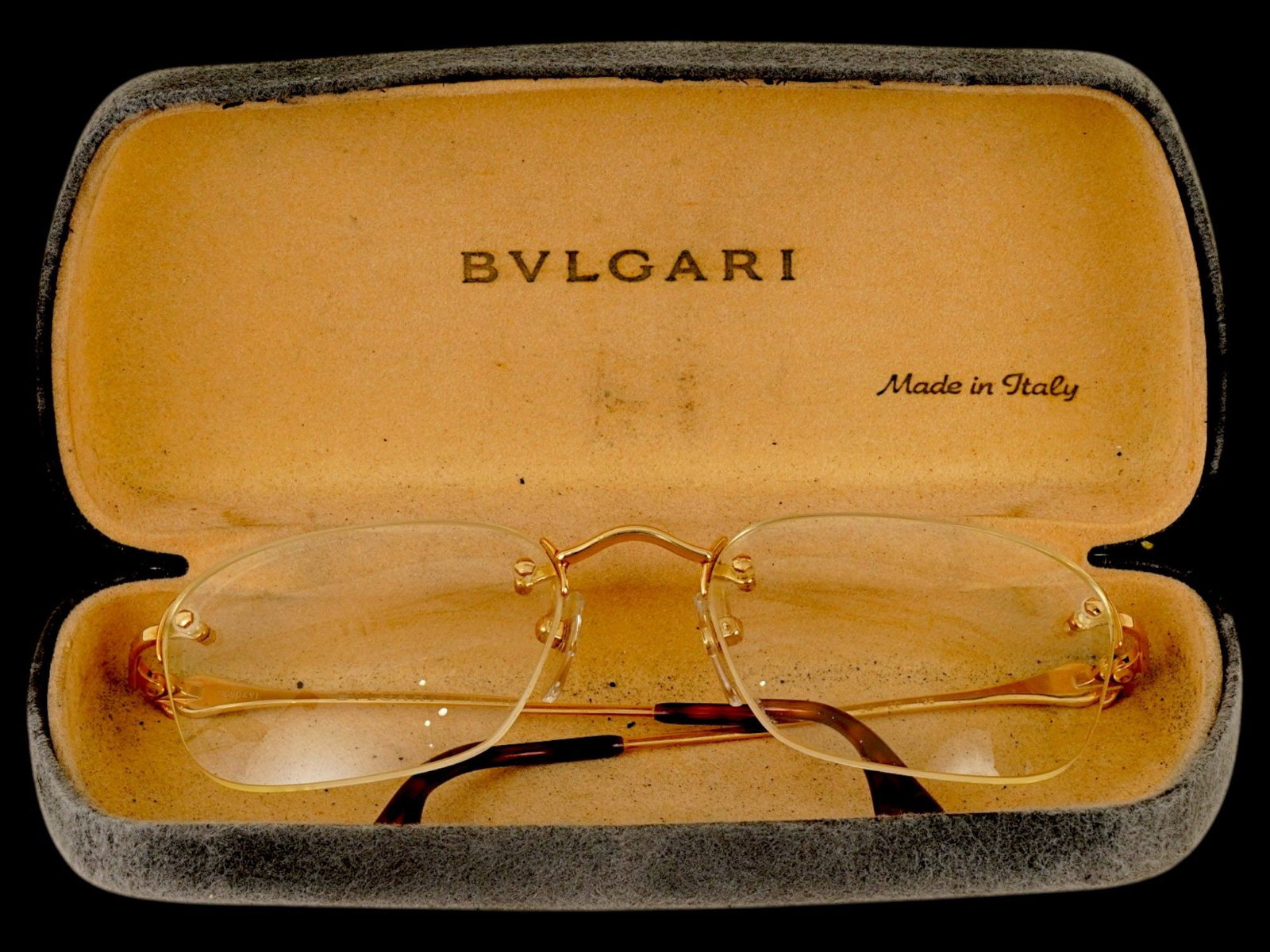 PAIR OF BVLGARI 18K GOLD RIMLESS READING GLASSES IOB: A pair of Bvlgari rimless reading glasses crafted with 18K gold components, characterized by elegant rectangular lenses and slim, refined temples. The hinges are accented with the houses signature cir