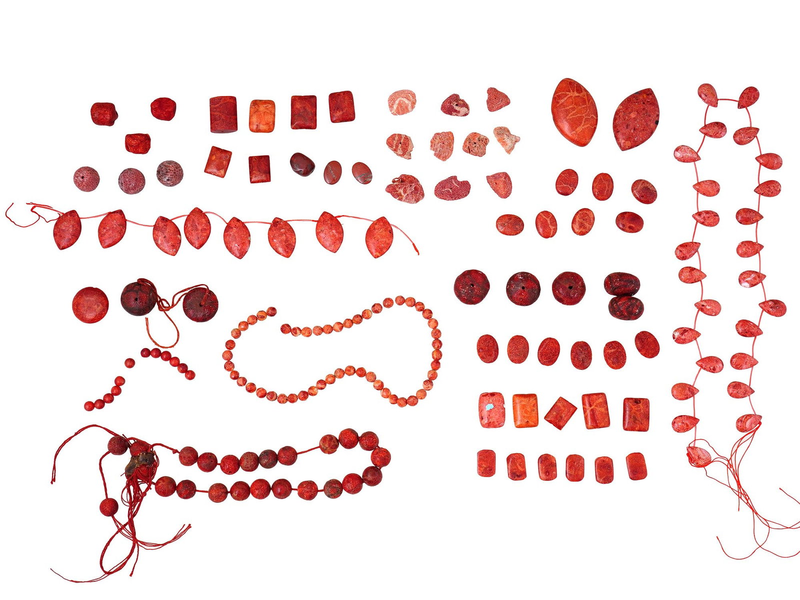 COLLECTION OF VARIOUS CORAL BEADS FOR JEWELRY: A collection of coral beads in various shapes and sizes. Some are loose, and others are strung on threads or partially assembled into necklaces or strands. The beads exhibit varying shades of red, ran
