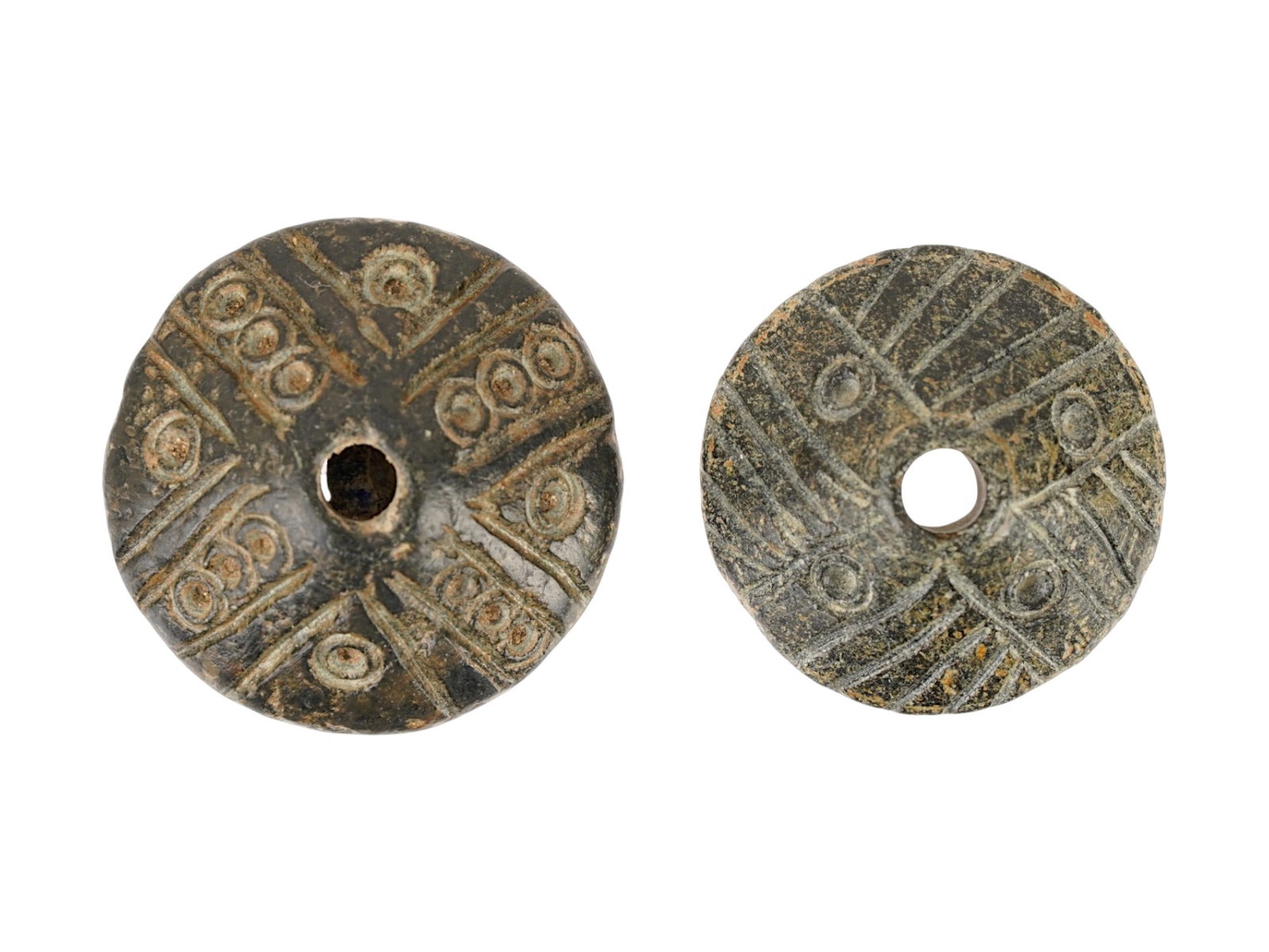 TWO ANCIENT BYZANTINE DARK STEATITE SPINDLE WHORLS: A lot of two ancient Byzantine hand carved dark steatite spindle whorls, dating ca. 400 to 600 AD. Each piece features a conical form with a central piercing for a spindle shaft, decorated with deeply