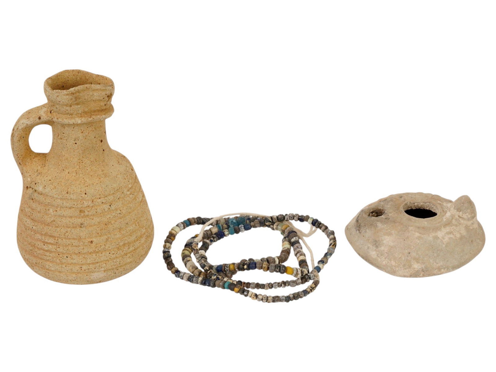 GROUP OF ANCIENT ROMAN TERACOTTA VESSELS AND NECKLACE: A lot of Ancient Roman artifacts. Imperial Rome era, ca. 100 to 300 AD. A total of 3 items. A glass beaded necklace. A terracotta oil lamp decorated with a dot pattern. A terracotta wine amphora, a ha