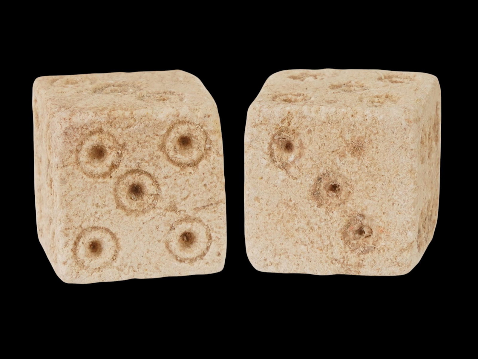PAIR OF ANCIENT ROMAN STONE DICE 100 TO 300 AD: A pair of ancient Roman hand carved stone dice, dating from 100 to 300 AD. These artifacts offer a tangible connection to the everyday life and leisure activities of the past. Carved from stone featur