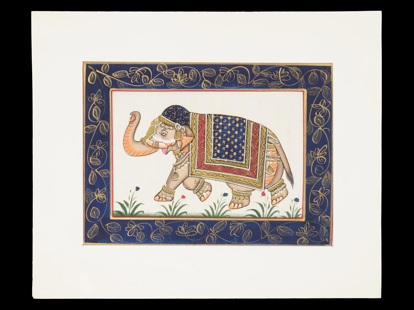 INDIAN RAJASTAN SCHOOL IMPERIAL ELEPHANT OIL PAINTING: An antique Indian Rajasthani School Mughal Art mixed media miniature painting on paper depicting an Imperial elephant painted in bold colors and with fine details, and gilded accents. Antique Indian P