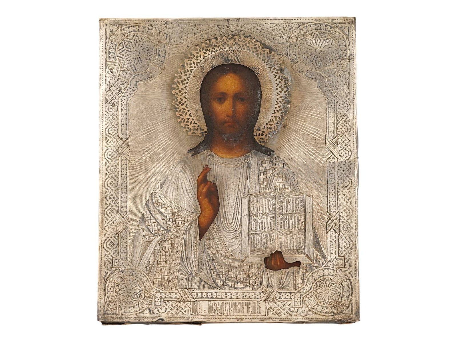 ANTIQUE RUSSIAN CHRIST PANTOCRATOR ICON IN SILVER OKLAD: An antique 19th century Russian Orthodox 84 silver icon of the Christ Pantocrator. Hand painted with egg tempera on a wooden board. The icon depicts Christ holding the New Testament in his left hand a