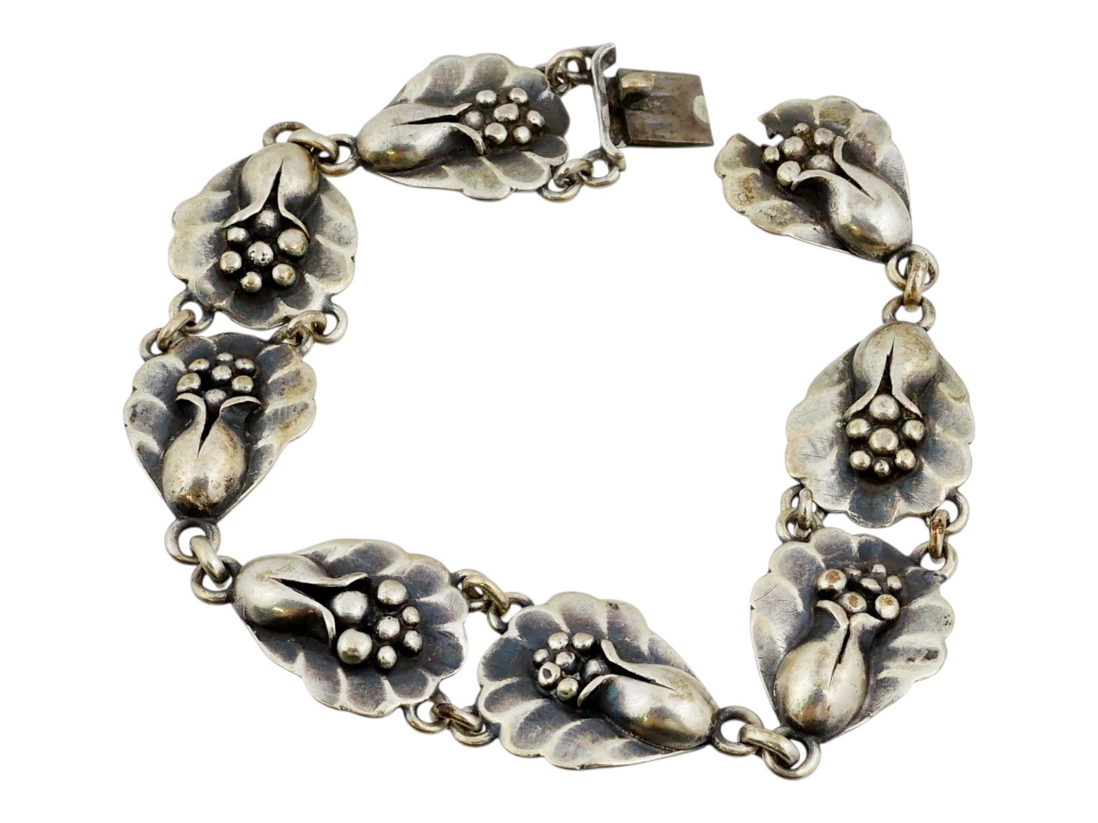 AFTER GEORG JENSEN FLORAL SILVER BRACELET: After Georg Jensen silver bracelet. This piece is composed of eight identical, stylized floral links. Each link is crafted with an Art Nouveau-influenced foliate motif, centered by a cluster of polish