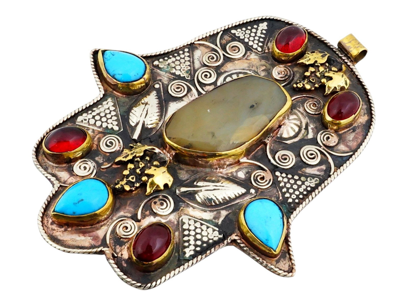 NEAR EASTERN SILVER COPPER HAMSA AMULET W GEMSTONES: A Near Eastern silver and copper Hamsa amulet. The amulet is modeled in the form of a stylized palm, decorated with relief motifs of foliage, vines and set with various gemstones. The hamsa is a palm-