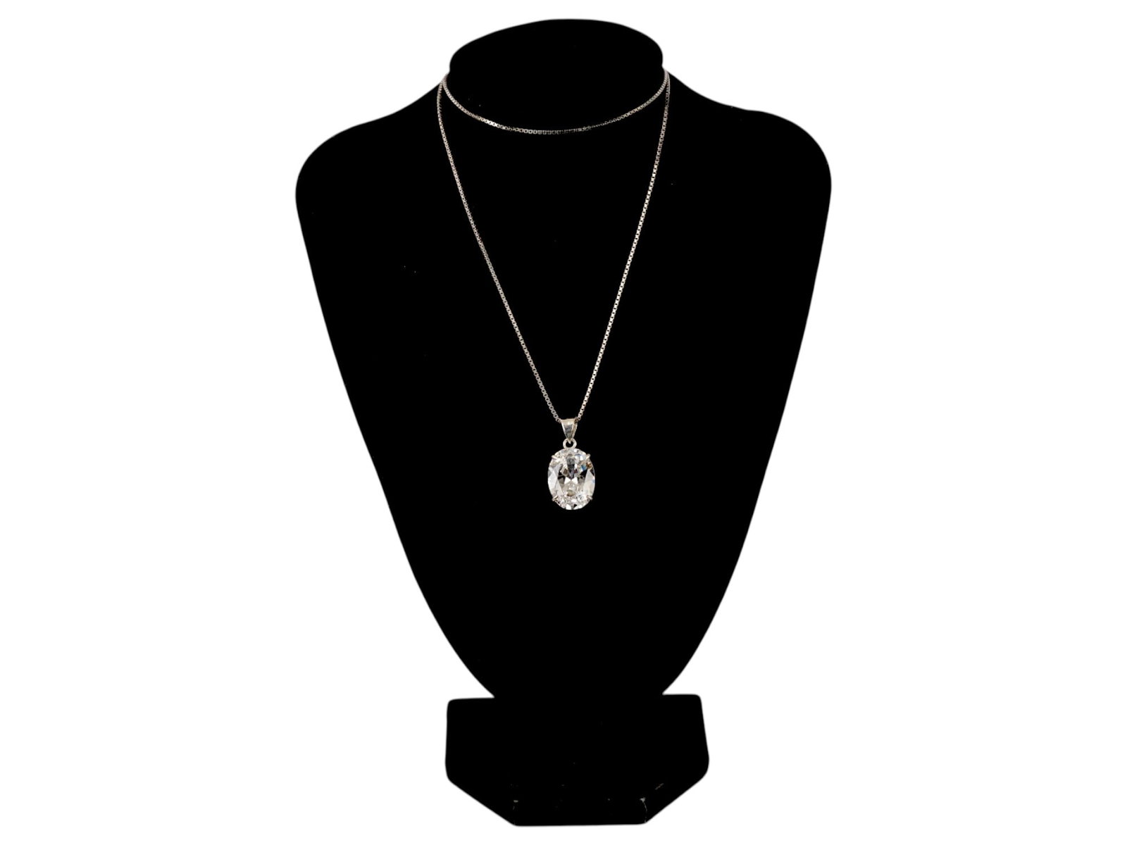 ELEGANT STERLING SILVER PENDANT NECKLACE WITH STONE: An elegant sterling silver pendant necklace features a prominent oval-cut colorless faceted stone, securely held by a four-prong basket setting. The pendant is made of silver and is paired with a fine