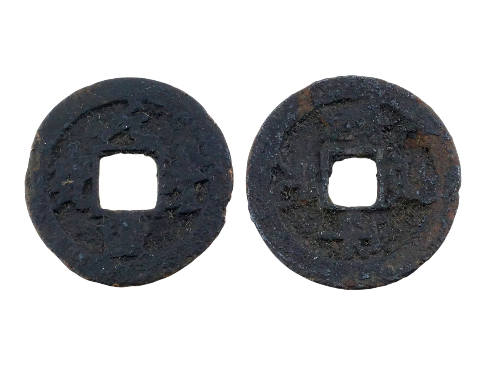 LOT OF TWO ANTIQUE CHINESE COINS: A lot of two antique Chinese coins, characterized by their circular form and central square apertures. Each piece displays an aged, dark patina and irregular rim edges, reflecting the historical sand-