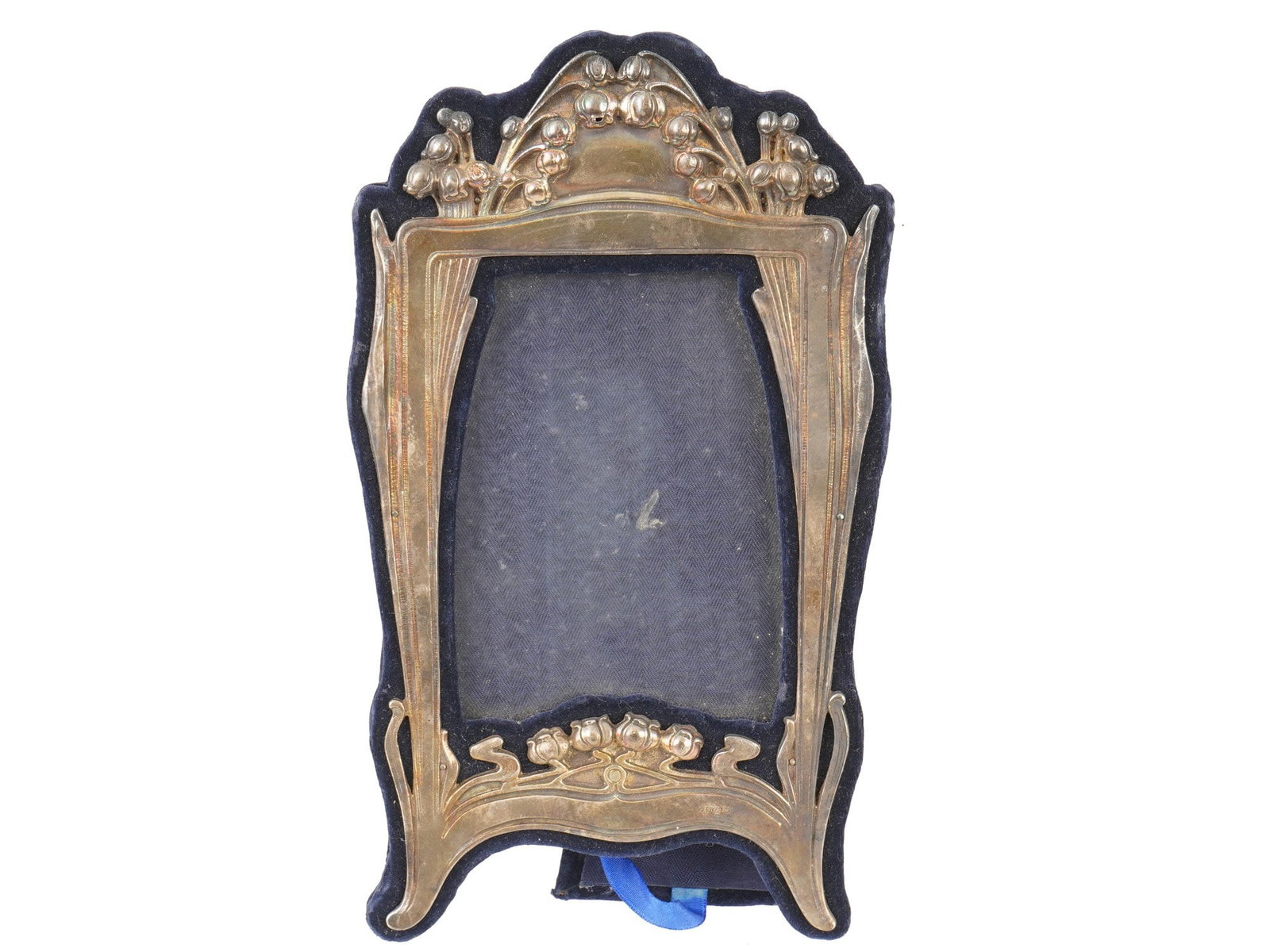 ART NOUVEAU MANNER FLORAL SILVER PICTURE FRAME: An Art Nouveau style Sterling Silver tabletop picture frame. The frame is adorned with an embossed design representing lily of the valley flowers, and a foliage motif on the sides. Marked with a