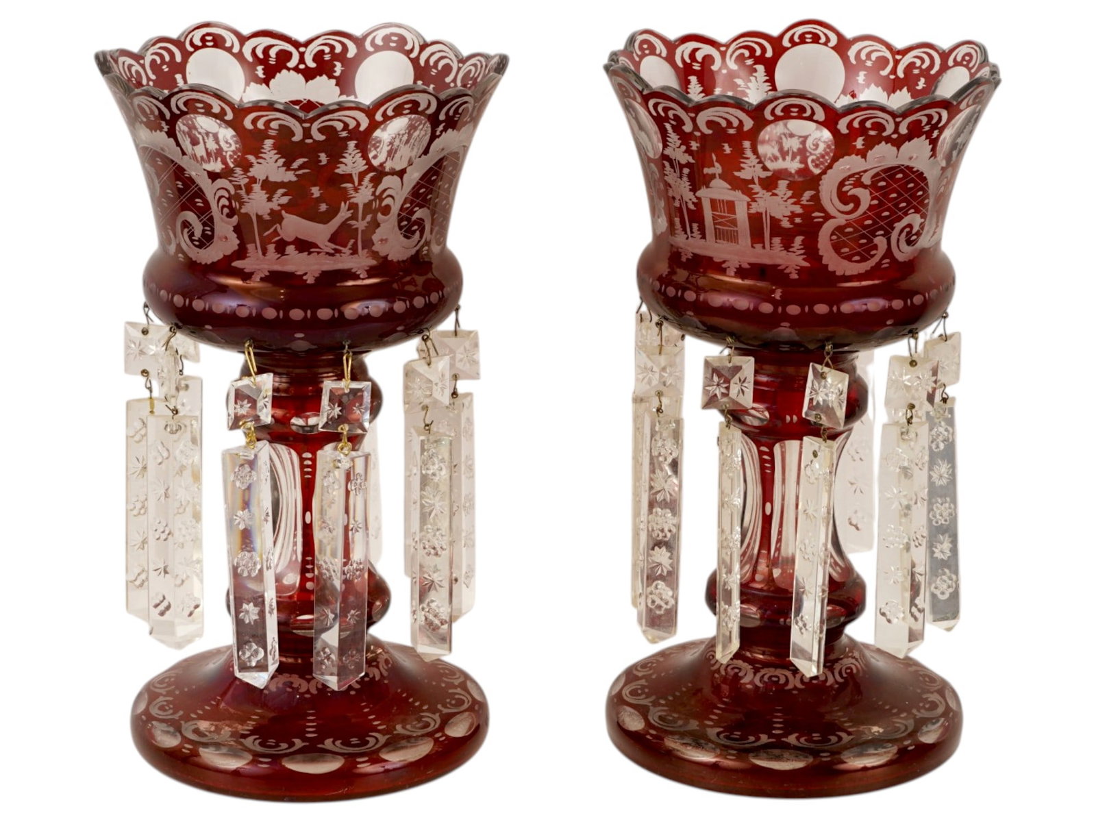 PAIR OF BOHEMIAN RUBY CUT TO CLEAR GLASS MANTEL LUSTERS: A pair of Bohemian ruby cut to clear glass mantel lusters features a deep cranberry red casing cut back to transparent glass with intricate etched floral, animal and scrollwork motifs. Each vessel is 