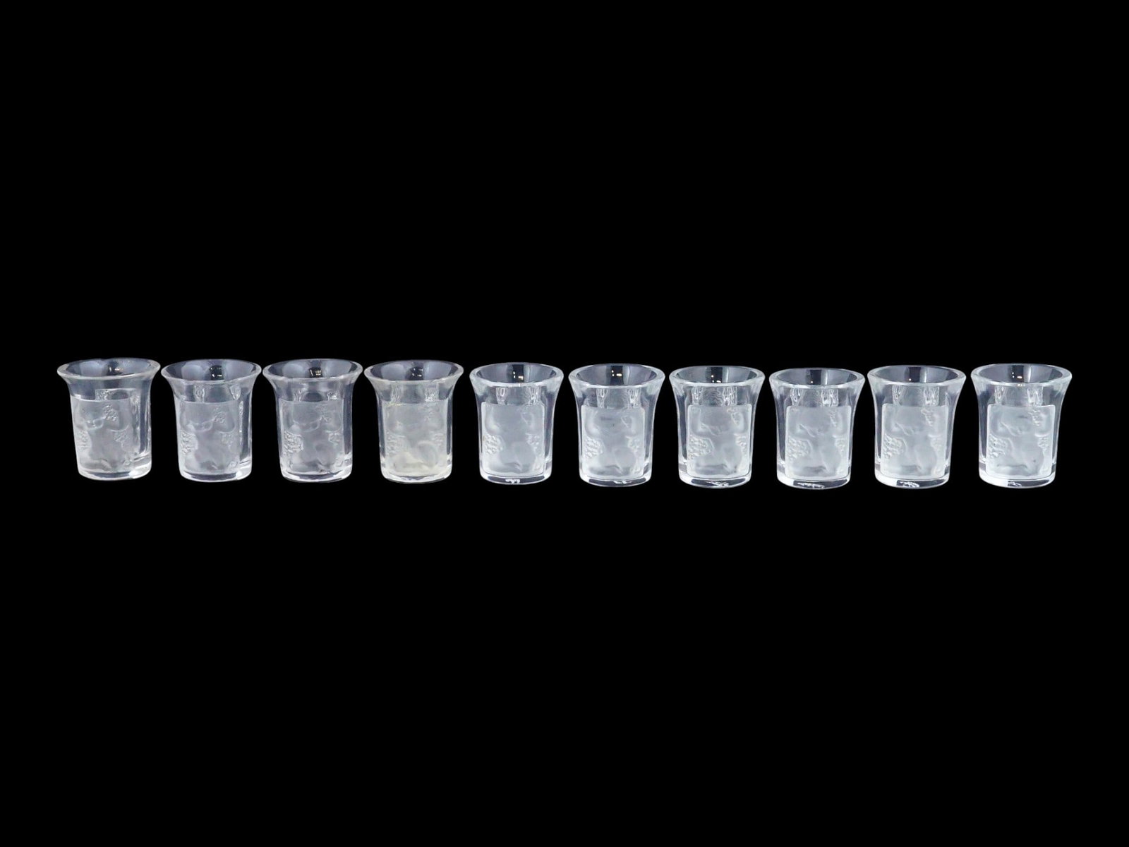 VINTAGE FRENCH LALIQUE ENFANTS CRYSTAL SHOT GLASSES: A set of ten vintage French Art Deco Enfants crystal shot glasses by Lalique, based on the celebrated 1932 design by Rene Lalique. Crafted in clear and frosted crystal, each glass features molded pane