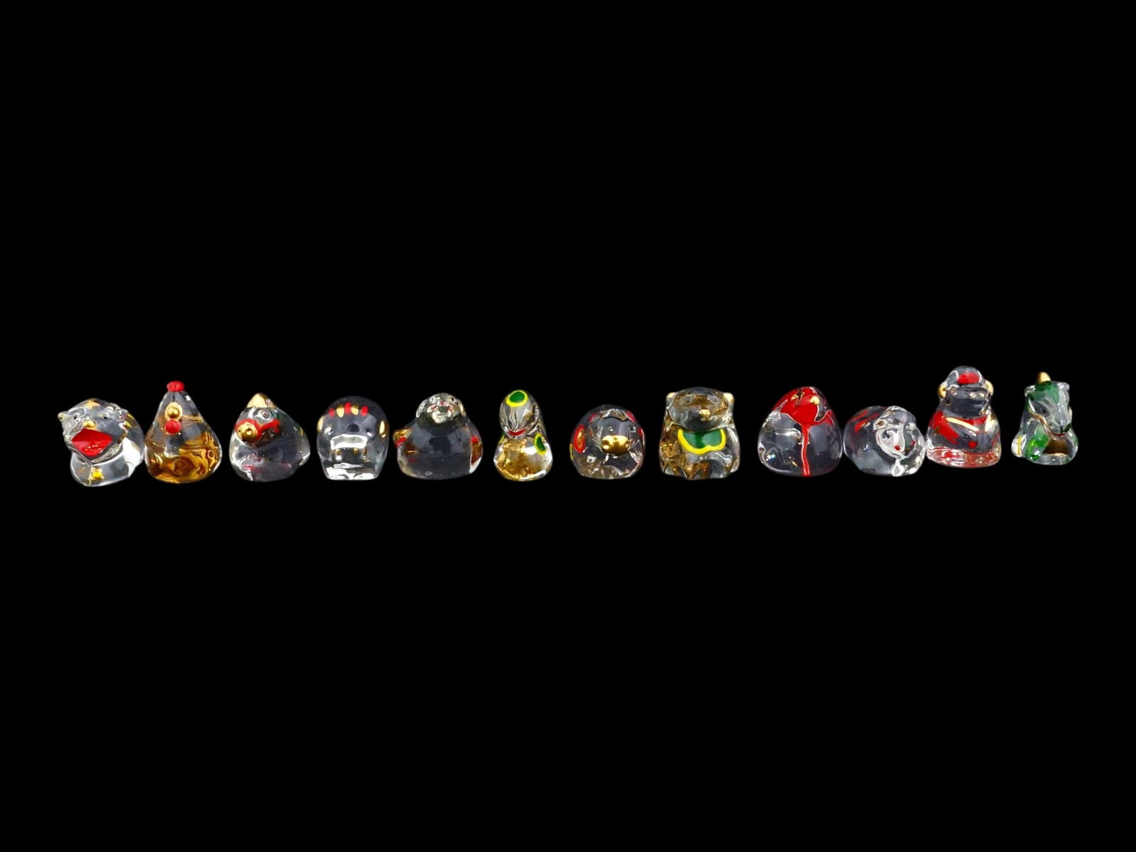COLLECTION OF CHINESE ZODIAC CRYSTAL ENAMEL FIGURINES: A collection of twelve Chinese Zodiac figurines, crafted from clear crystal style glass, each featuring intricate internal and external polychrome enamel decoration. The collection includes the tradit
